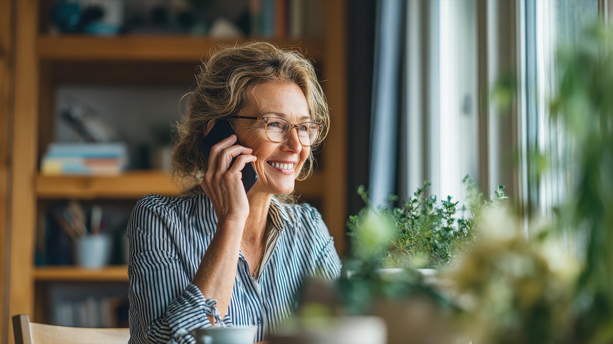 A woman smiling during a warm phone conversation at home, talking through her recovery plan